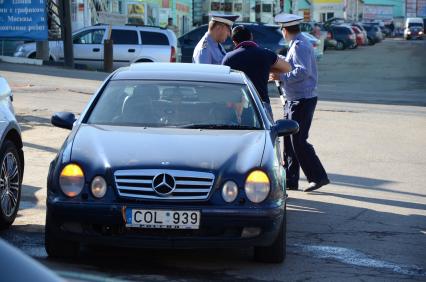 42-ой километр Калужского шоссе. Cотрудники Управления охраны общественного порядка (УООП)  провели рейд `Нелегальный мигрант`. В ходе проверки ТК `Славянский мир` обнаружен поселок нелегальных мигрантов. На снимке: сотрудники полиции у автомобиля Mercedes