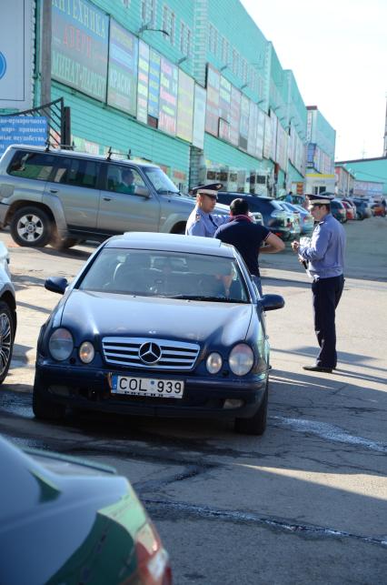 42-ой километр Калужского шоссе. Cотрудники Управления охраны общественного порядка (УООП)  провели рейд `Нелегальный мигрант`. В ходе проверки ТК `Славянский мир` обнаружен поселок нелегальных мигрантов. На снимке: сотрудники полиции у автомобиля Mercedes