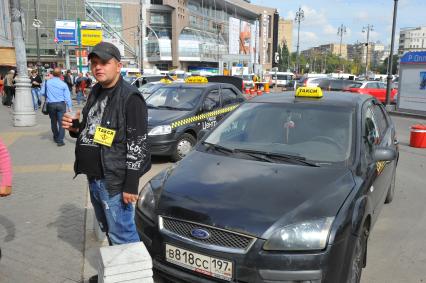 Стоянка такси. На снимке: таксист и автомобили.