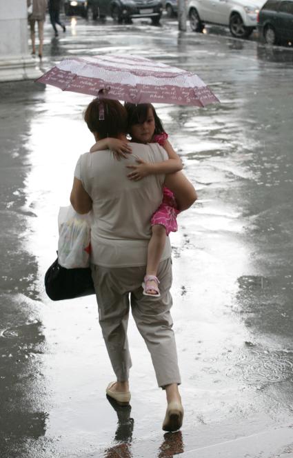 Дождь в городе. На снимке: женщина с ребенком  под зонтом.
