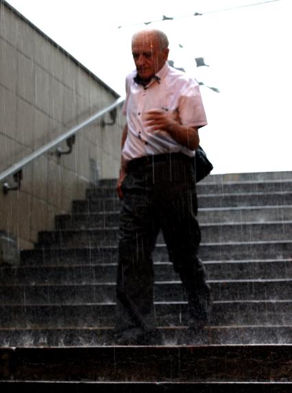 Дождь в городе. На снимке: мужчина на лестнице
