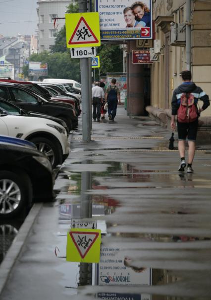 Город после дождя. На снимке: прохожие и автомобили.