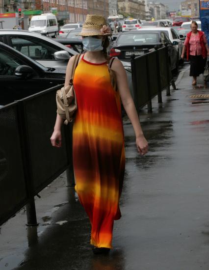 Женщина с медицинской маской на лице идет по улице.