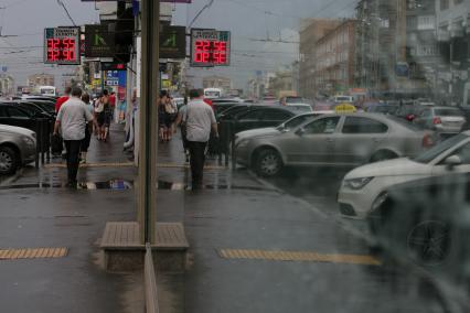 Прохожие и автомобили  отражаются в витрине здания.