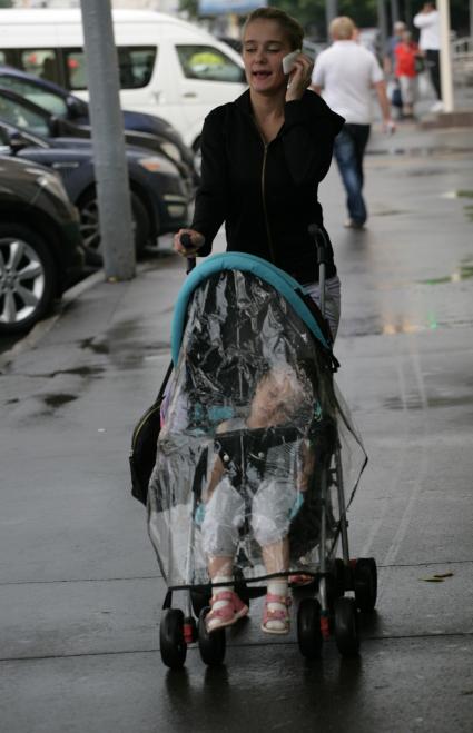 Разговор по мобильному телефону. На снимке: женщина с ребенком в детской коляске.