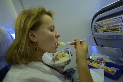 Самолет авиакомпании `Оренэир` (Оренбургские авиалинии). На снимке: девушка обедает в самолете.