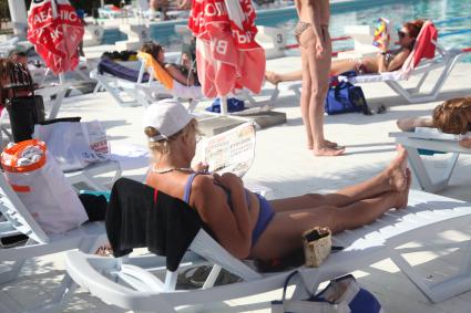 Диск80. \"Кинотавр\" 2013 год. На снимке: женщина на лежаке возле бассейна читает \"Экспресс газету\"