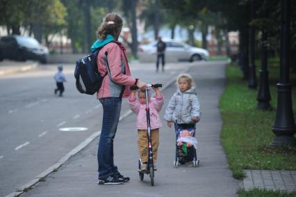 Мама с детьми гуляют в Петровском парке.