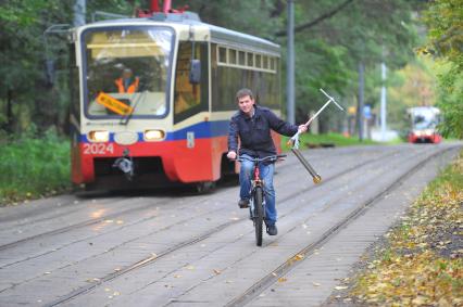 День отказа от автомобиля. На снимке: мужчина едет на велосипеде и держит  в руке самокат.