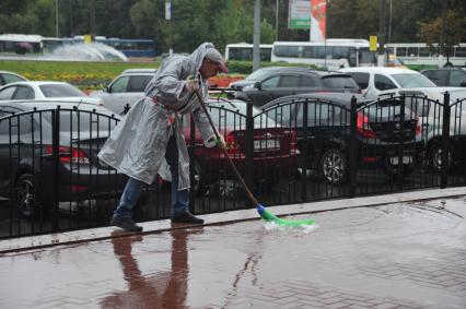 Ливень в городе. На снимке: дворик метлой убирает воду с тротуара.