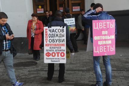 Живая реклама. На снимке:  мужчины с рекламными плакатами `Ремонт часов, одежды, обуви` и `Цветы по оптовым ценам`