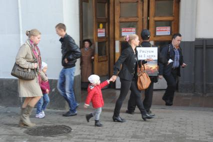 Живая реклама. На снимке: женщина с ребенком идет мимо мужчины с рекламным плакатом `Рисуем за 1 день`