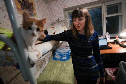 Студенческое общежитие в Екатеринбурге. На снимке: девушка гладит кота сидящего на втором ярусе кровати.