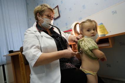 Медицинский осмотр детей в детском садике. На снимке: медицинский ребенок проверяет состояние легких ребенка с помощью стетоскопа.