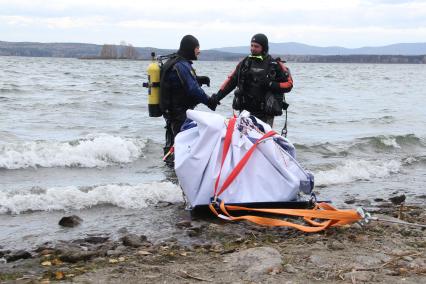 Водолазы вытаскивают из воды метеорит с помощью лебедки.