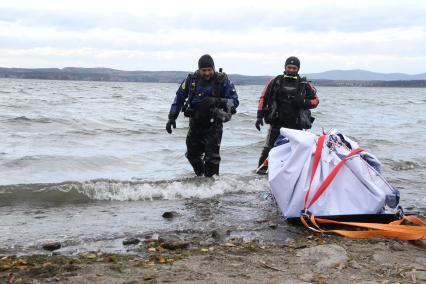 Водолазы вытаскивают из воды метеорит с помощью лебедки.