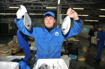 Профессиональная продажа морепродуктов и охлажденной рыбы. Склад рыбной продукции компании  `La Maree`.  На снимке: рабочий держит в руках рыбу.