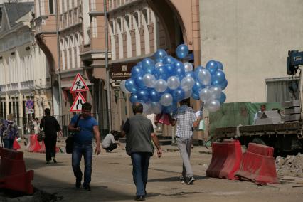 Улица Большая Дмитровка. Дорожно-ремонтные работы по замене асфальта. На снимке: мужчина несет связку воздушных шаров.
