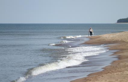 Мужчина с тростью идет по берегу Балтийского моря