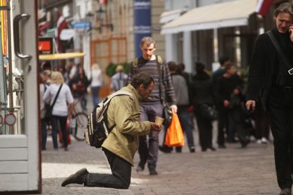 Мужчина на коленях проит милостыню на одной из улиц Риги