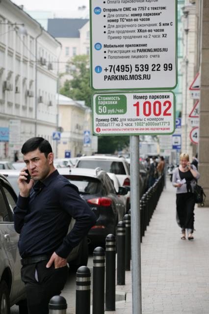 Московский паркинг. На снимке: мужчина с мобильным телефоном у щита `Правила пользования городскими парковками`.