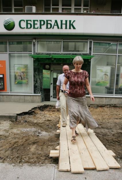 Отделение Сбербанка. На снимке:  люди идут по деревянному настилу.