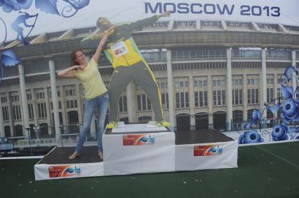 СК `Лужники`. Чемпионат мира по легкой атлетике 2013. На снимке: девушка на пьедестале рядом с картонной фигурой ямайского спортсмена Усэйна Болта