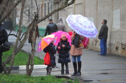 Дождь в городе. На снимке: женщина и девочки под зонтами.