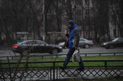 Первый снег.  На снимке: мужчина несет в руках стаканчик с кофе.