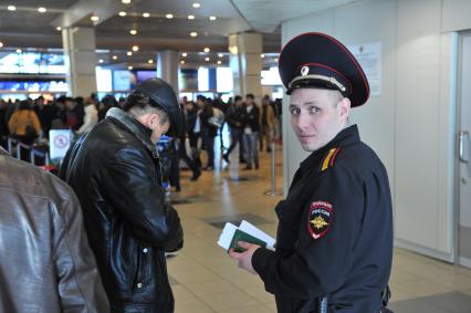 Аэропорт `Домодедово`. На снимке: сотрудник полиции проводит проверку документов у пассажира