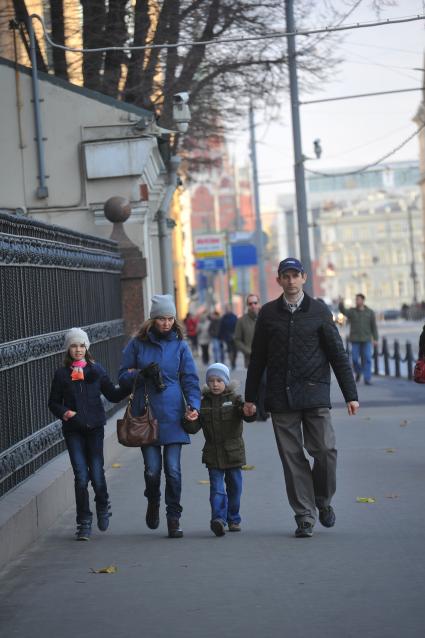 Мужчина и женщина с детьми на городской улице.