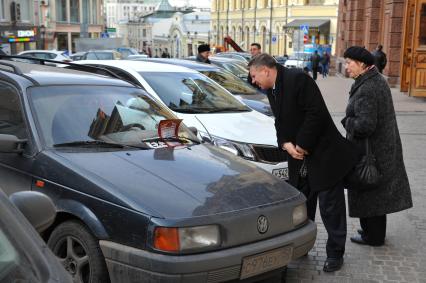 Рейд участников движения `Рассерженные горожане`. Припаркованный автомобиль со скрытым регистрационным номером. На снимке: прохожие разглядыват   грамоту `Жлоба` на лобовом стекле машины.