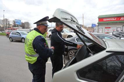 Сотрудники ДПС провели операцию `Осмотр и досмотр автомобилей` на Мичуринском проспекте. На снимке: водитель демонстрирует сотруднику ДПС багажник машины.