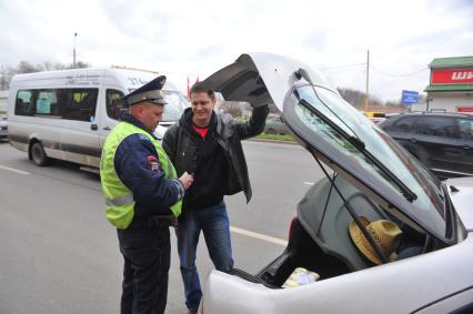 Сотрудники ДПС провели операцию `Осмотр и досмотр автомобилей` на Мичуринском проспекте. На снимке: водитель демонстрирует сотруднику ДПС багажник машины.