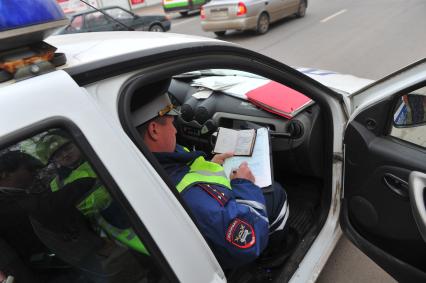 Сотрудники ДПС провели операцию `Осмотр и досмотр автомобилей` на Мичуринском проспекте. На снимке: сотрудник ДПС составляет протокол.