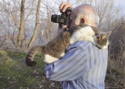 Василий Михайлович Песков с котом на плече фотографирует природу.