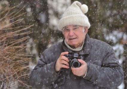 Василий Михайлович Песков с фотоаппаратом во время снегопада в воронежском лесу.