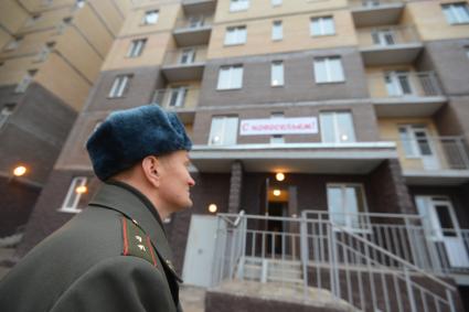 Жилье военным. Офицер перед подъездом дома.