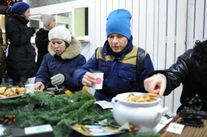 Станция `Теплое место` открылась в Столешниковом переулке. На снимке: люди едят за столом.