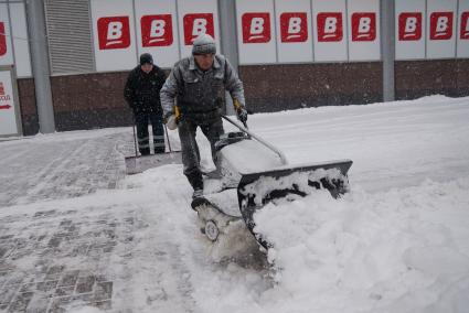 Снегопад в Екатеринбурге. На снимке: дворники расчищают улицу с помощью бензинового снегоуборщика около продуктового магазина `Верный`.