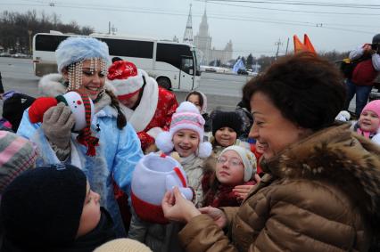 Новогодняя акция КП на смотровой площадке Воробьевых гор. На снимке: корреспондент КП Олег Адамович и телеведущая КП Арина Горшкова раздают подарки детям.