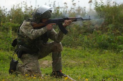 Боец выполняет стрельбу из положения сидя.