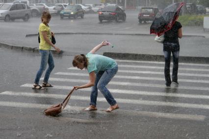 Девушка уронила сумку в лужу на пешеходном переходе.