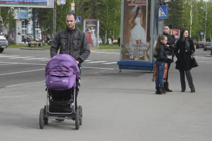 Мужчина на прогулке с детской коляской.