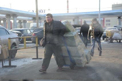 Рынок `Садовод`. На снимке: мужчина везет груз на тележке