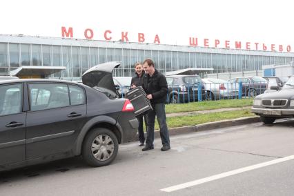 Аэропорт Шереметьево. На снимке: водитель-частник загружает чемодан пассажирки в багажник автомобиля.