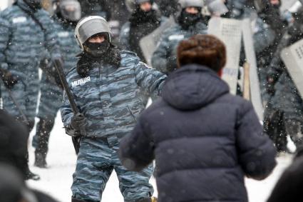 Сотрудник милиции с дубинкой напротив протестующих.