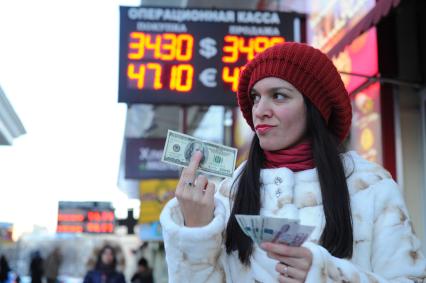 Девушка с деньгами около пункта обмена валюты.