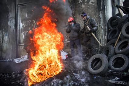 Протестующие греются около костра из автомобильных покрышек.