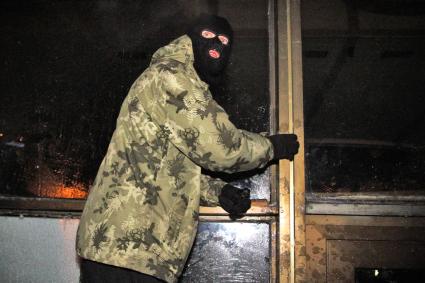 Протестующие штурмуют Украинский дом. На снимке: протестующий в маскировочной шапке у входа в здание.